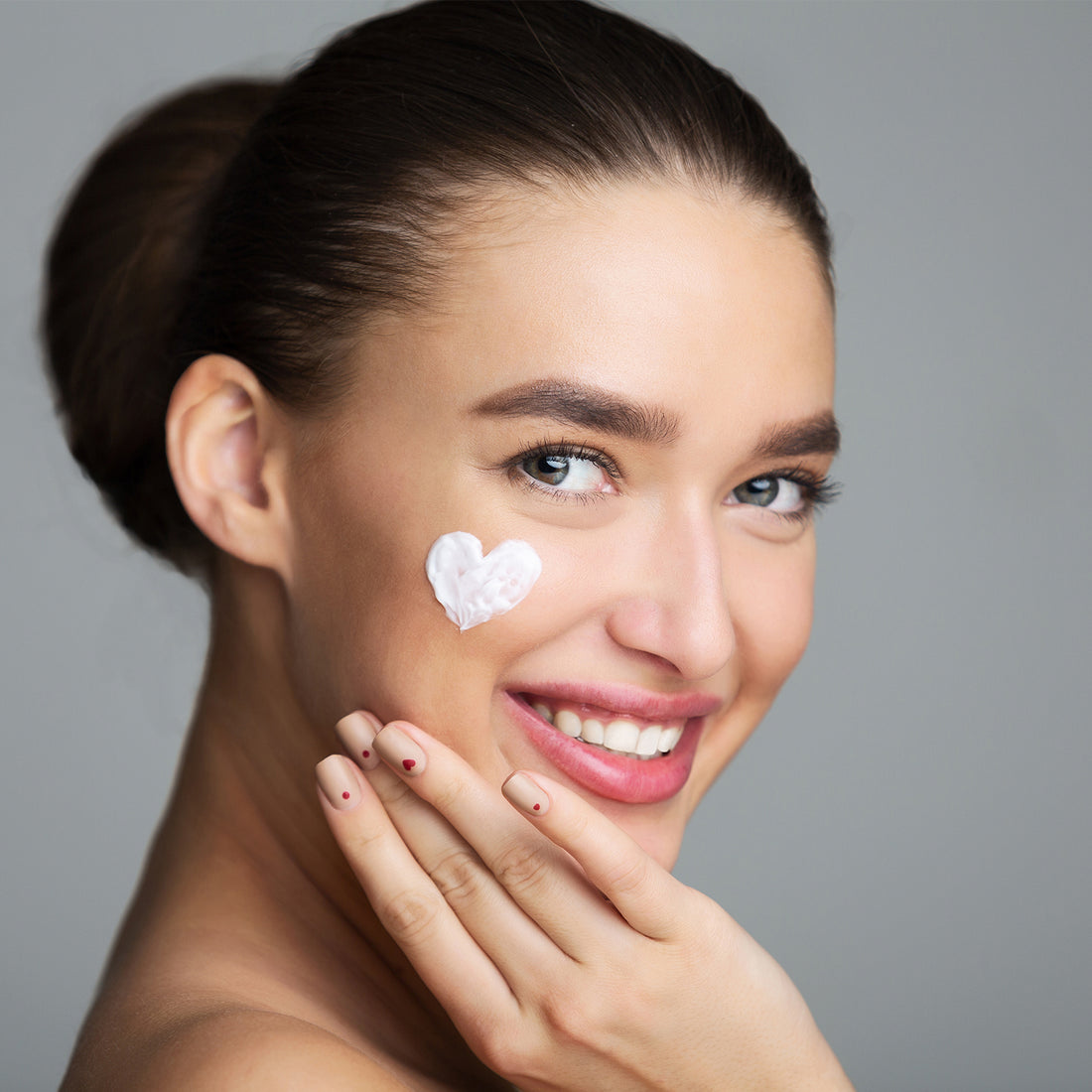 A gorgeous woman with cream on her face, applying a spot corrector to achieve a radiant, clear, and acne-free skin.